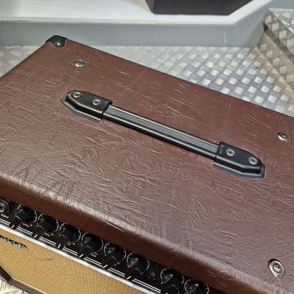 Pre-Owned Hartwood HW-AA-30 Close-up of the side of a brown textured amplifier or speaker cabinet with a black handle, metal screws, and part of the tan speaker grille visible.