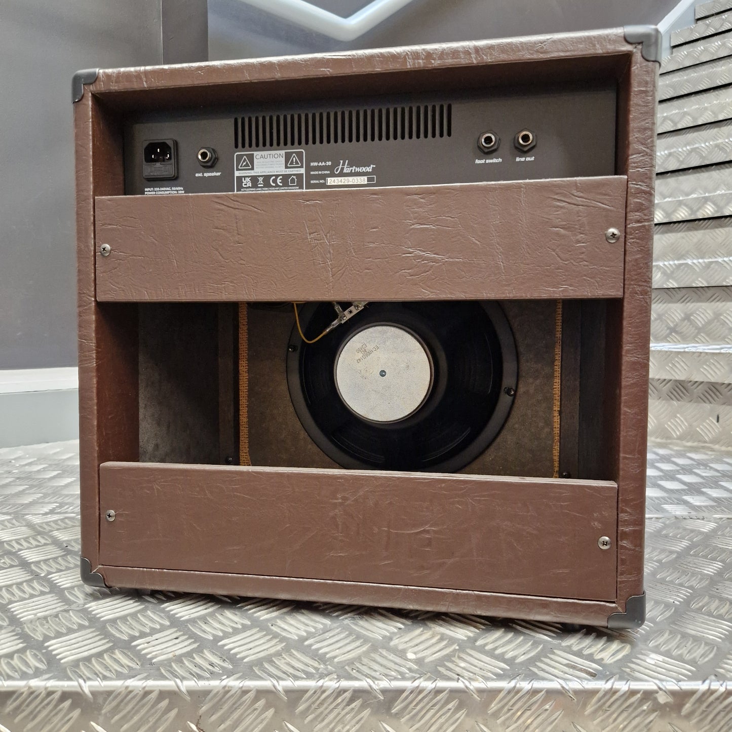 Pre-Owned Hartwood HW-AA-30 A brown textured speaker cabinet shown from an angled top-down view, featuring a visible speaker driver inside and the rear input panel on the left side.