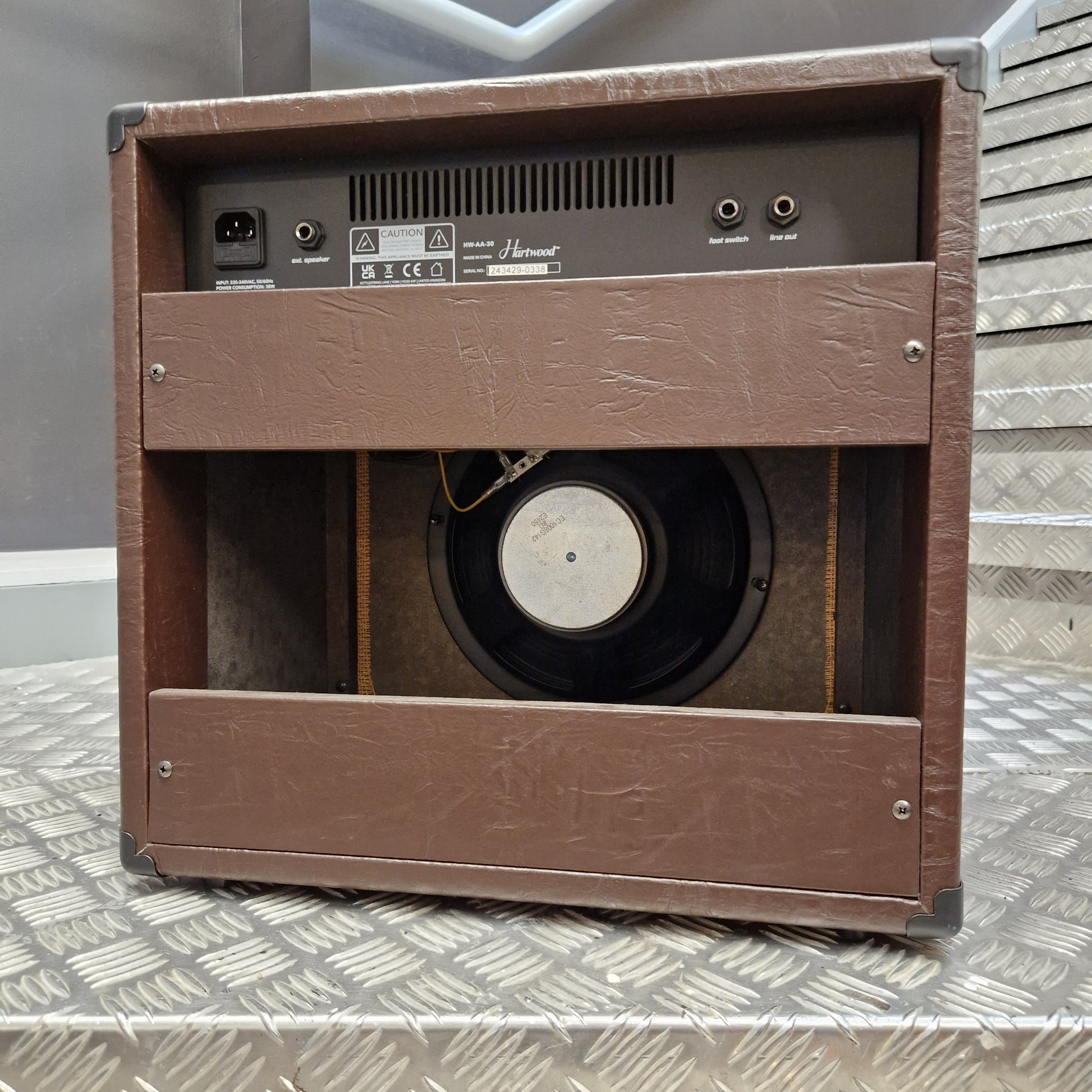 Pre-Owned Hartwood HW-AA-30 A brown textured speaker cabinet shown from an angled top-down view, featuring a visible speaker driver inside and the rear input panel on the left side.