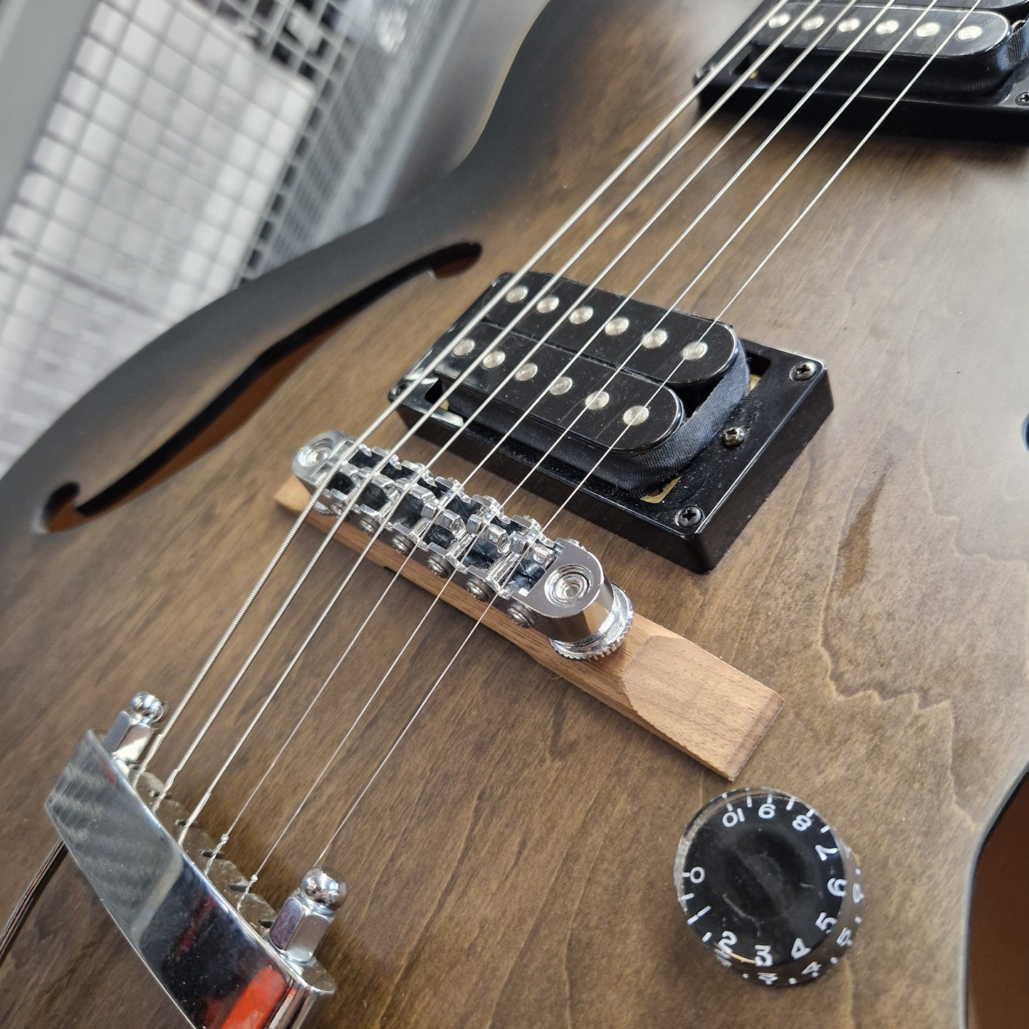 Pre-Owned Ibanez AF55-TKF Hollowbody Electric - Black Flat Close-up of a wooden electric guitar body showing the bridge, pickups, strings, and control knob on a natural wood finish.