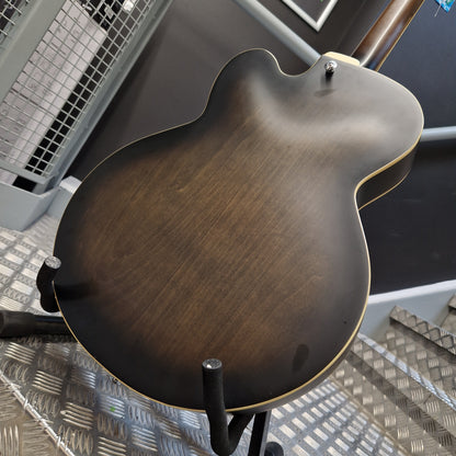 Pre-Owned Ibanez AF55-TKF Hollowbody Electric - Black Flat Close-up of the back of an electric guitar body with a dark brown sunburst finish, mounted on a stand in a workshop setting.