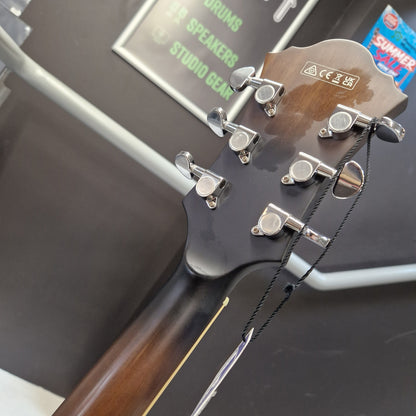 Pre-Owned Ibanez AF55-TKF Hollowbody Electric - Black Flat Close-up of the headstock of a wooden acoustic guitar, showing six silver tuning pegs and a black string with a metal tuner attached. The headstock has a glossy dark brown finish with a small white logo plate.