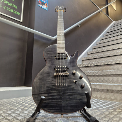 Pre-Owned Chapman ML-2 Electric - Grey A black electric guitar with a glossy flamed maple top and dark finish, resting on a stand in an indoor showroom with acoustic panels and stairs in the background.