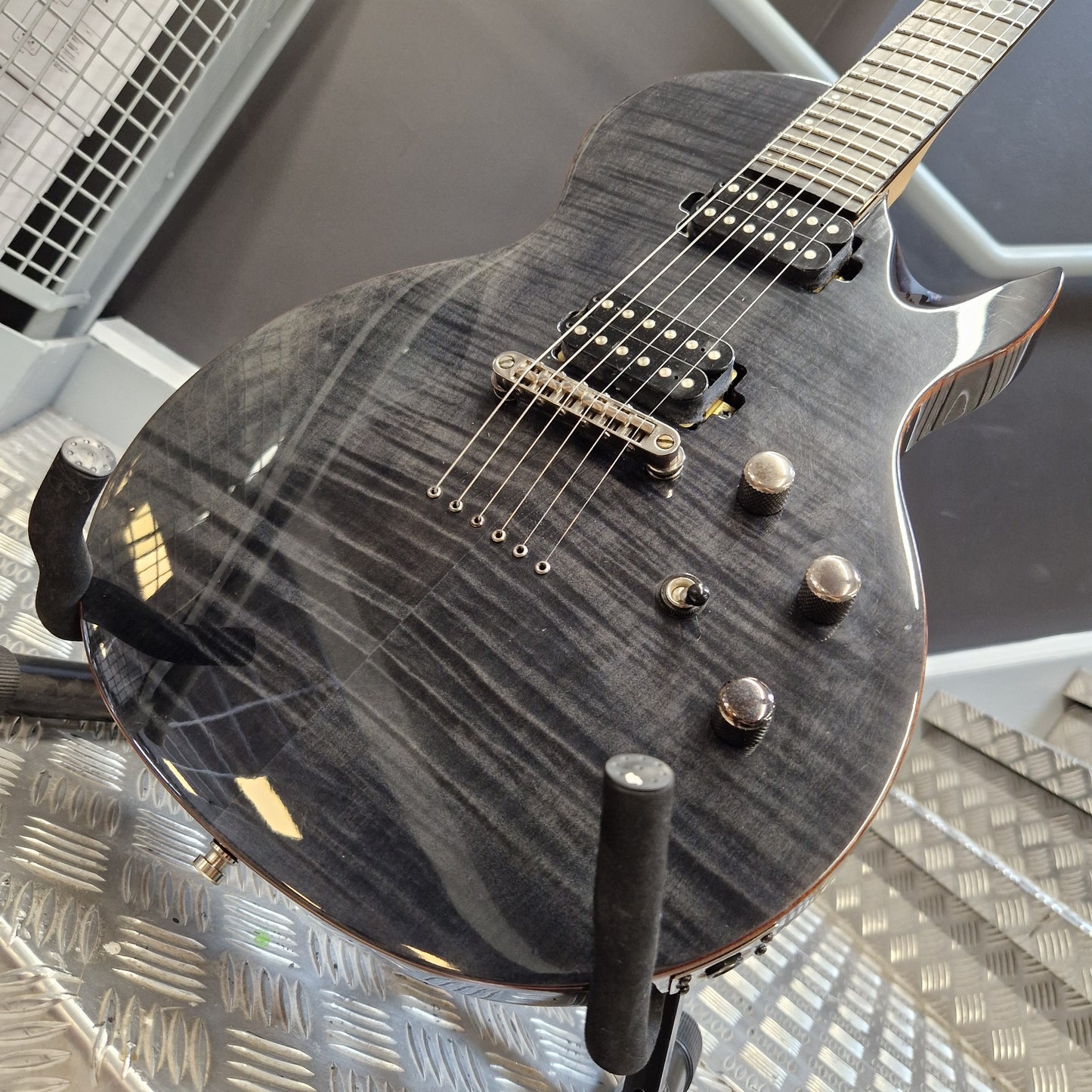 Pre-Owned Chapman ML-2 Electric - Grey Close-up of an electric guitar body in a dark gray flamed maple finish, showing the pickups, control knobs, and part of the neck, photographed indoors against a gray and metallic background.