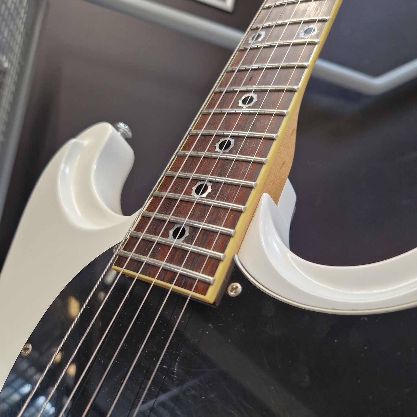 Pre-Owned Schecter Shaun Morgan Signature Electric - White Close-up of an electric guitar showing the white body, black pickguard, dark wood fretboard, and light wood headstock inlay.