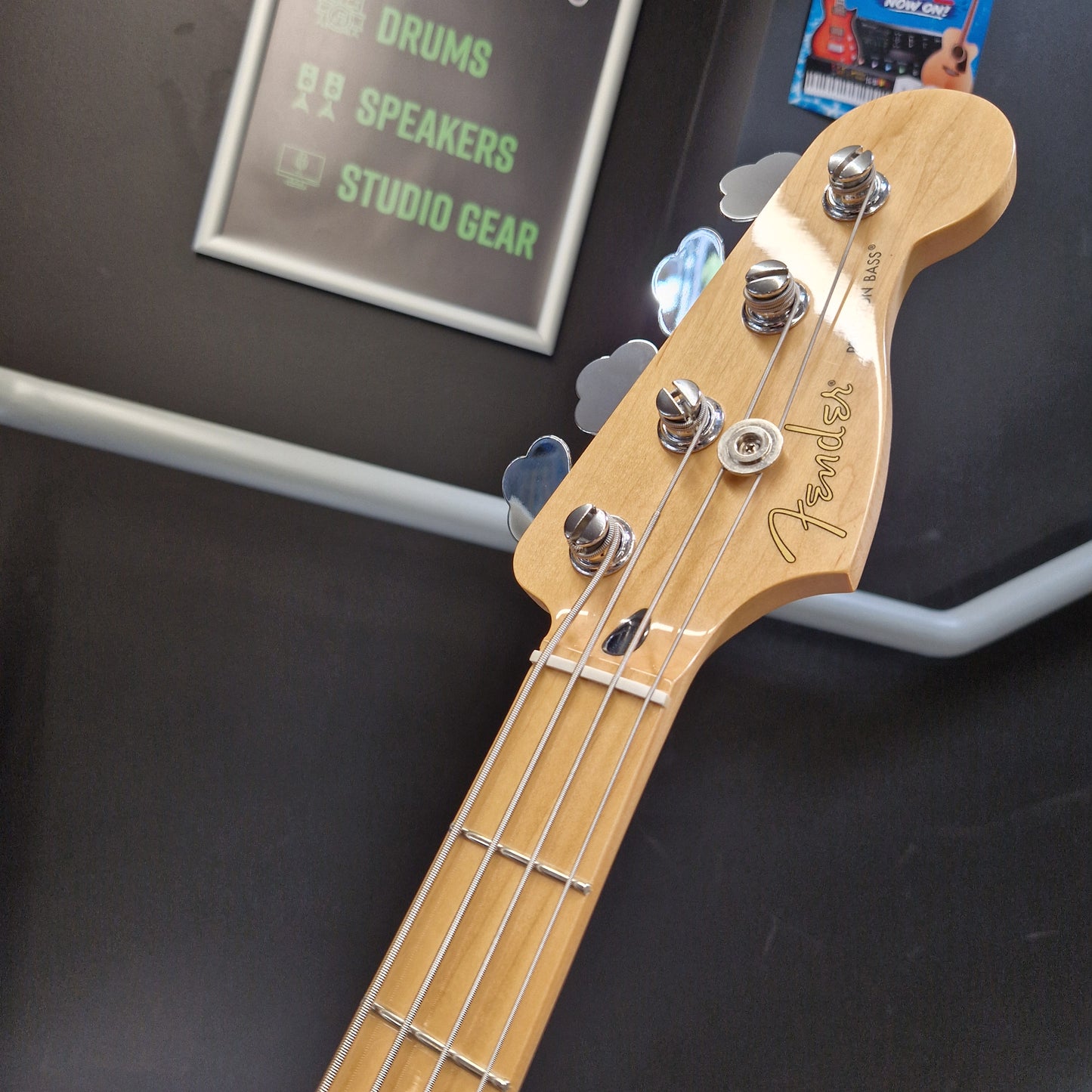 Pre-Owned Fender Player Precision Bass - Limited Edition Electron Green Close-up of a Fender bass guitar headstock and neck, showing the natural wood finish, four tuning pegs, and four strings against a dark display background.