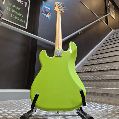 Pre-Owned Fender Player Precision Bass - Limited Edition Electron Green A bright lime green electric bass guitar with a natural wood neck, displayed on a black stand inside what appears to be a showroom or studio.