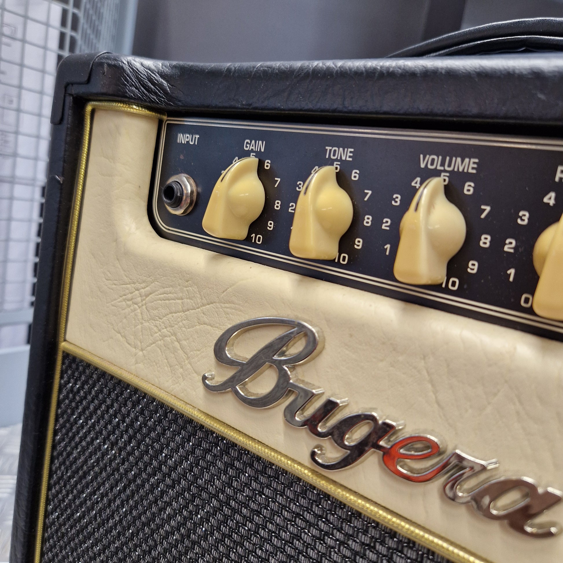 Pre-Owned Bugera Vintage 5 V5 Valve Guitar Combo Close-up of a Bigner electric guitar amplifier head, showing cream-colored textured controls, black knobs, a black mesh grille, and a chrome script logo.