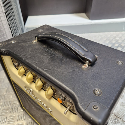 Pre-Owned Bugera Vintage 5 V5 Valve Guitar Combo Close-up of a black leatherette guitar amplifier cover with a black handle, cream-colored knobs, and metal screws, shown on a textured metal surface.