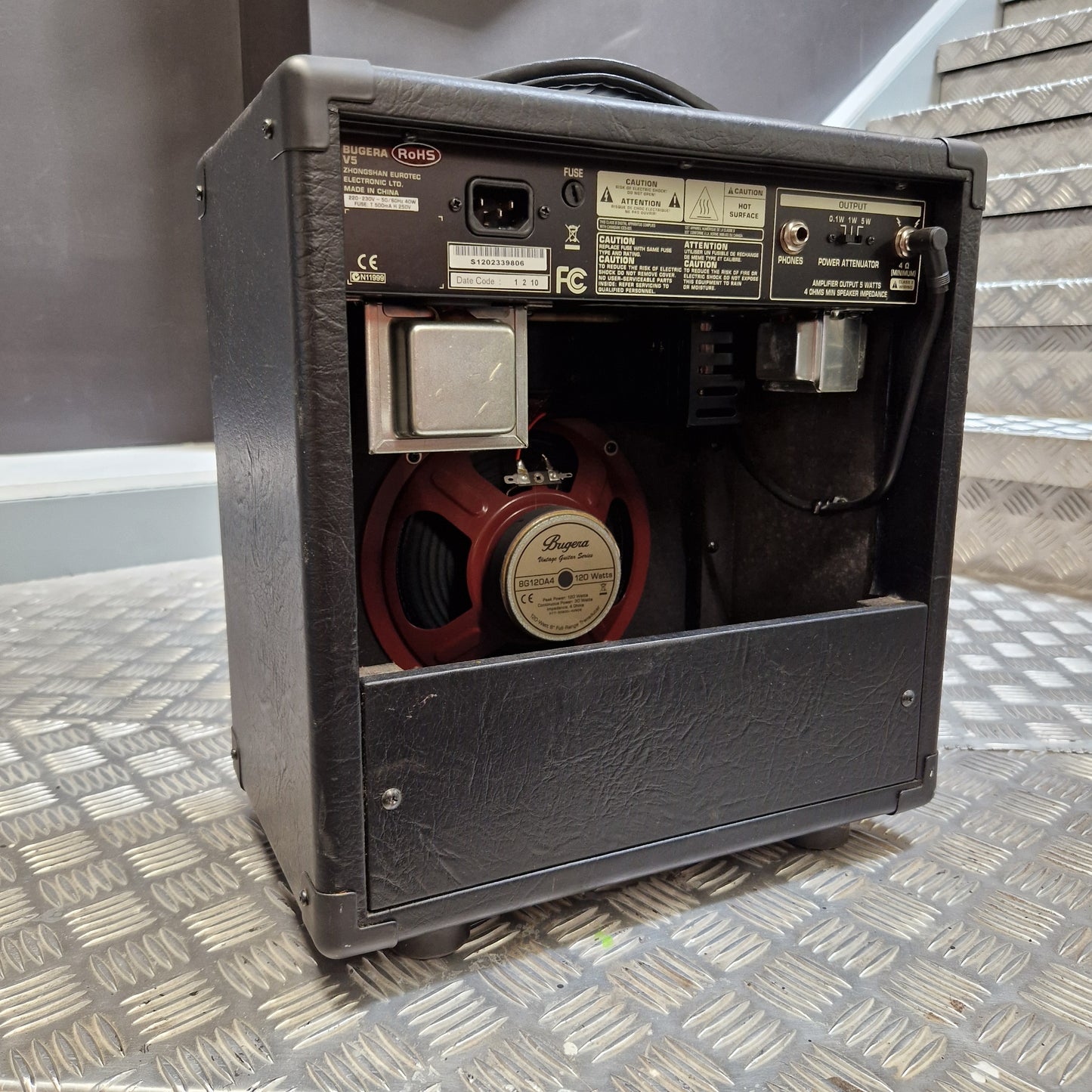 Pre-Owned Bugera Vintage 5 V5 Valve Guitar Combo A black guitar amplifier cabinet with its top cover open, showing the internal speaker, power supply components, and control panel. The amplifier is photographed on a textured gray diamond-plate metal surface.