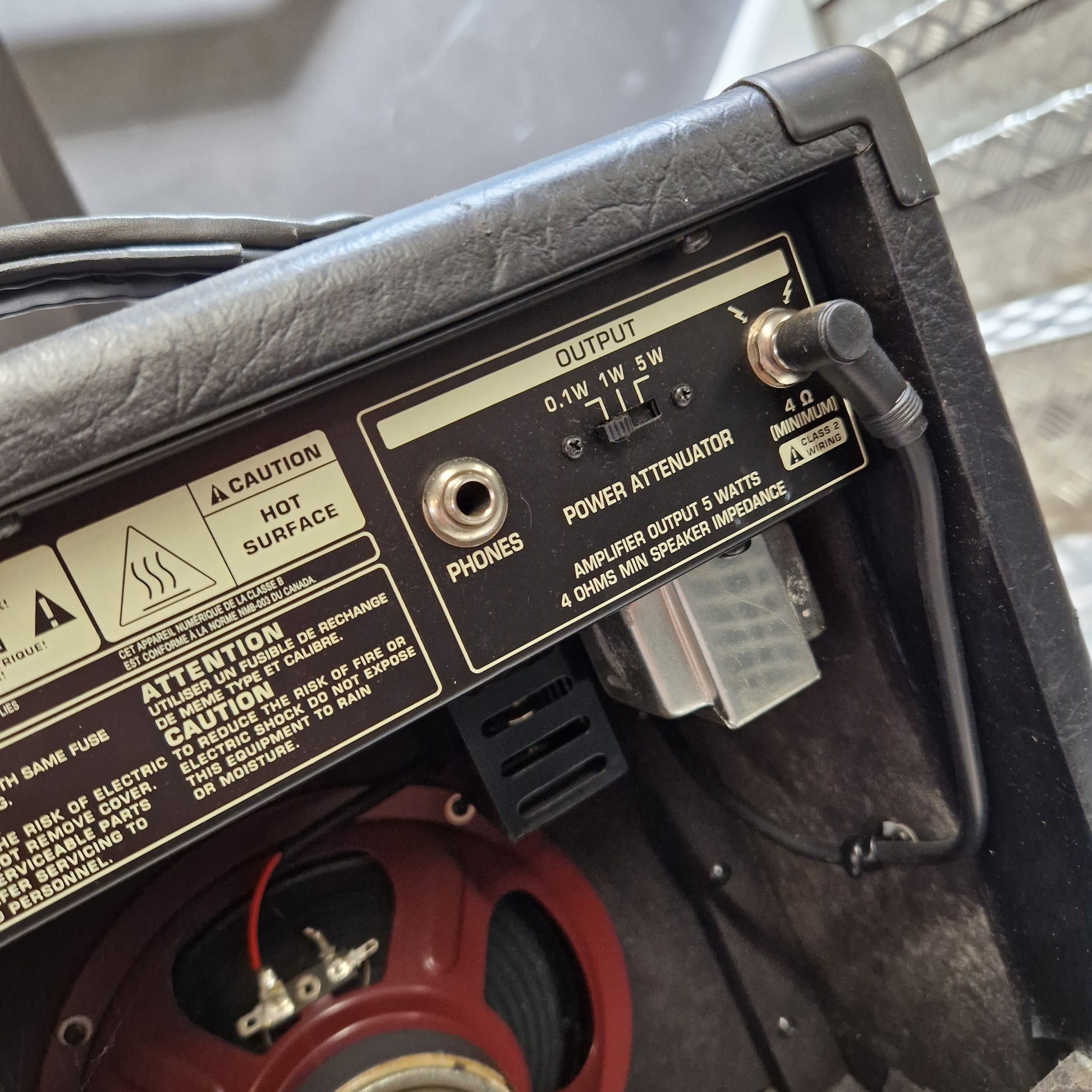 Pre-Owned Bugera Vintage 5 V5 Valve Guitar Combo Close-up of the rear panel of a black guitar amplifier or speaker cabinet, showing controls, labels, and a red speaker cone inside.