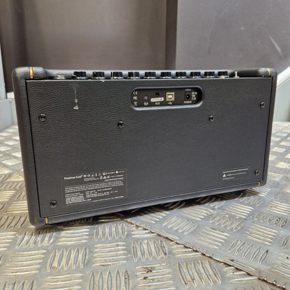 Pre-Owned Positive Grid Spark 40-Watt Smart Guitar Combo & Bluetooth Speaker The back of a black portable speaker, showing the input jacks, power switch, and model label, resting on a diamond plate metal surface.