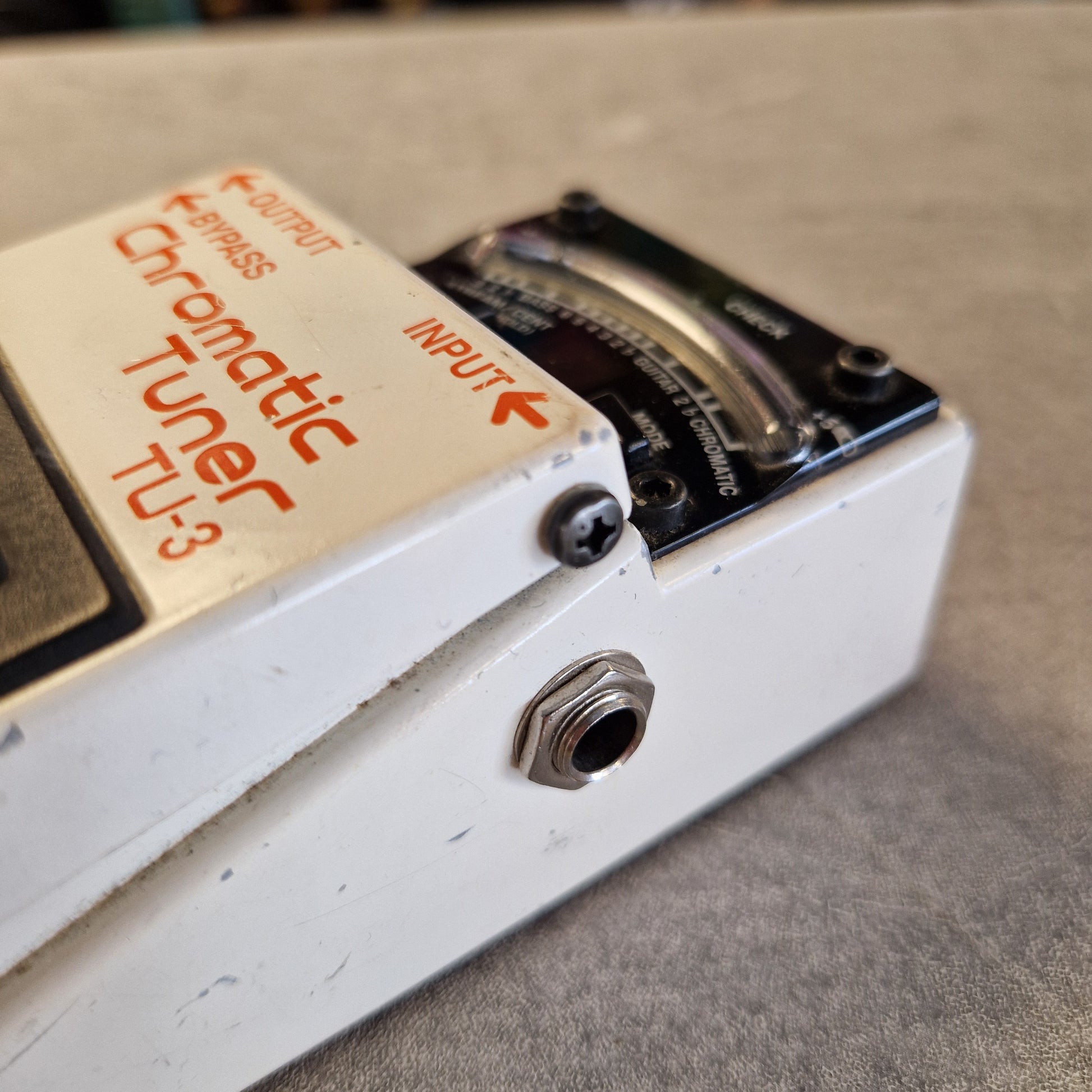 Pre-Owned Boss TU-3 Tuner Pedal Close-up of a white Chromatic Tuner TU-3 guitar pedal with orange lettering, showing the input jack, output jack, and part of the black chromatic tuner dial.