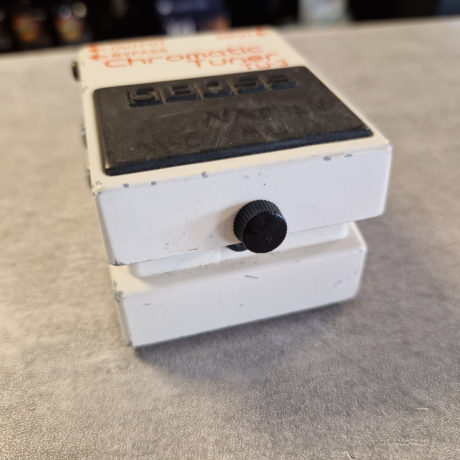 Pre-Owned Boss TU-3 Tuner Pedal A white guitar effects pedal with a black control knob and a black label panel, photographed at an angle on a gray textured surface.