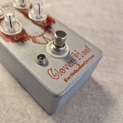 Pre-Owned EarthQuaker Devices Cloven Hoof Fuzz Pedal Close-up of an Earthquake Devices Clover Haze guitar effects pedal with a textured gray metal casing, red logo text, and a silver footswitch on a neutral gray background.