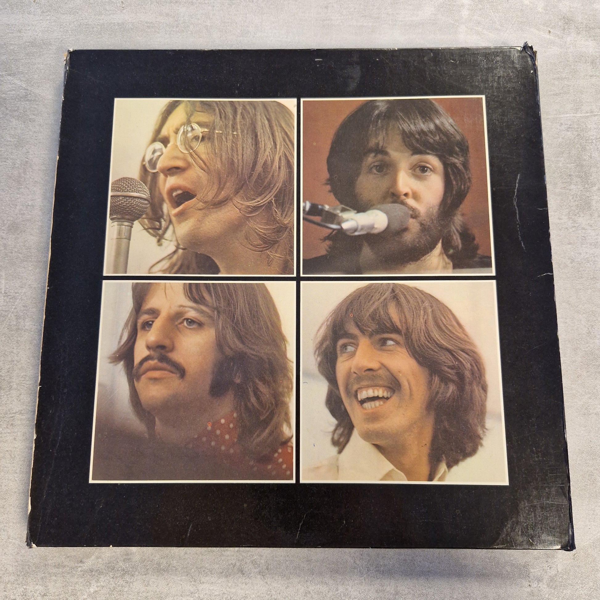 The Beatles - Let It Be (Limited Edition) Vintage Vinyl Boxset A square black album cover or book-style package with four vintage portrait photos arranged in a 2x2 grid, photographed on a light gray textured surface.