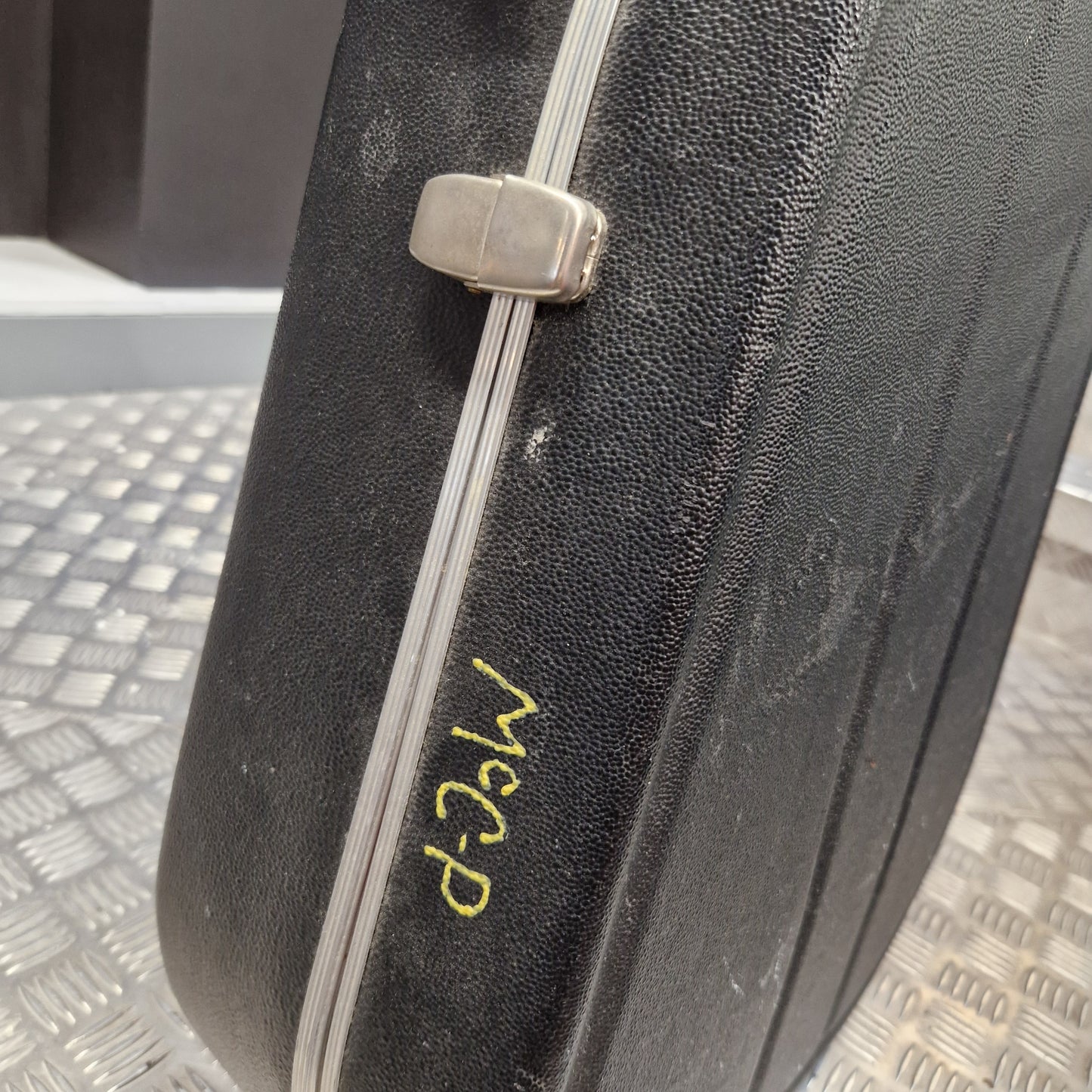 Pre-Owned Hiscox LiteFlite Acoustic Hard Case A close-up of a black textured hard case with a silver metal latch and a yellow handwritten marking reading 'MCP'.