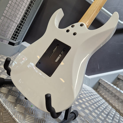 Pre-Owned Ibanez RG350DX Electric - White A close-up of a white electric guitar body on a stand, showing the back plate, black pickup cover, control holes, and part of a natural wood neck.