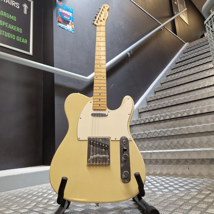 Pre-Owned Squier MIK 1996 Telecaster Electric - Blonde A cream-colored electric guitar with a maple neck and black hardware, displayed on a stand in an indoor stairwell environment.