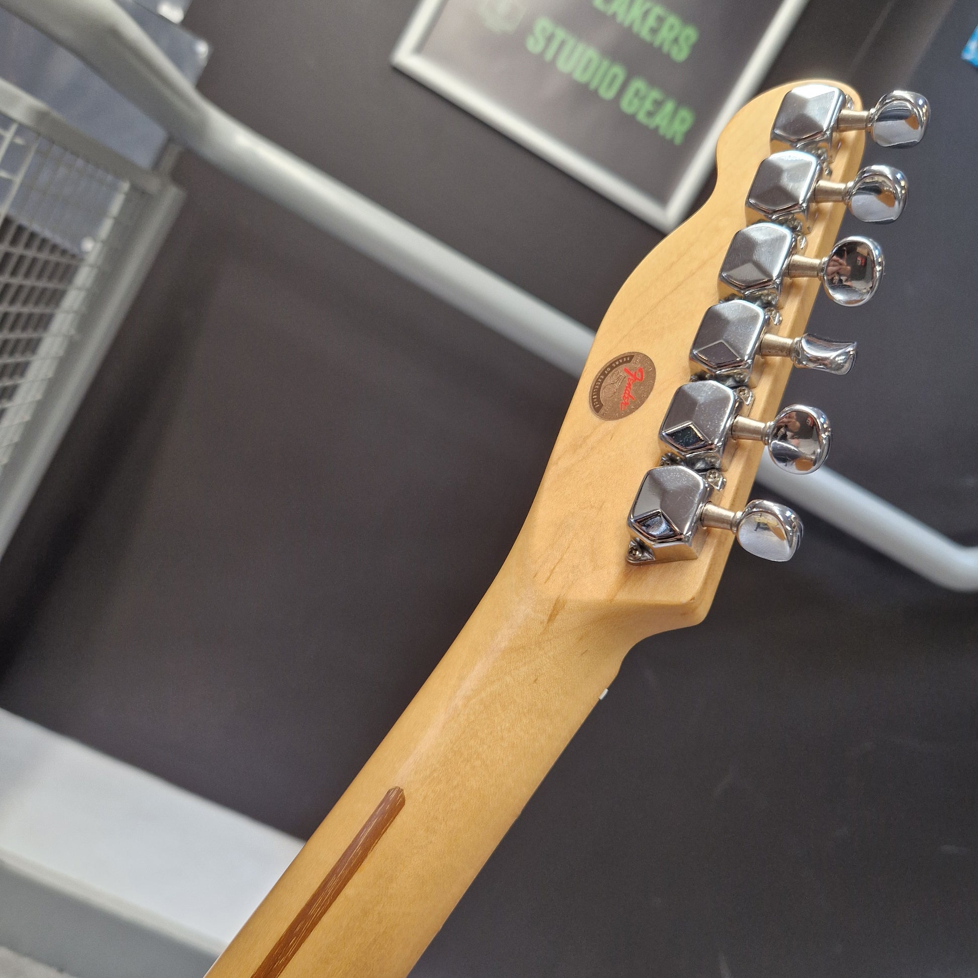 Pre-Owned Squier MIK 1996 Telecaster Electric - Blonde Close-up of the headstock of a Fender electric guitar in a natural maple finish, showing the six silver tuning pegs and a small red Fender logo badge, set against a dark gray background.