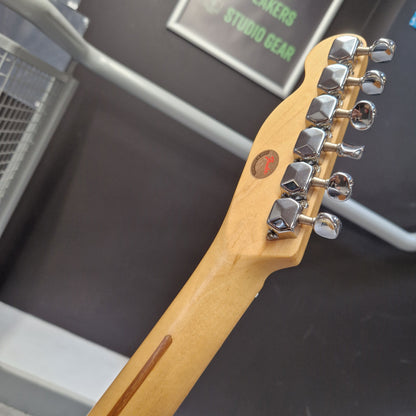 Pre-Owned Squier MIK 1996 Telecaster Electric - Blonde Close-up of the headstock of a Fender electric guitar in a natural maple finish, showing the six silver tuning pegs and a small red Fender logo badge, set against a dark gray background.
