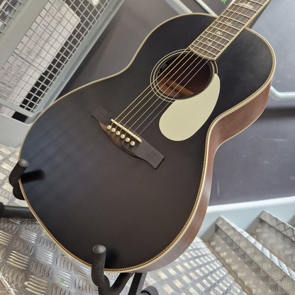 Pre-Owned PRS P20 Tonare Parlor Electro-Acoustic - Black A close-up of an acoustic guitar body on a stand, featuring a dark brown to black varnished finish, a cream pickguard, and gold-toned hardware, photographed in what appears to be a showroom or studio setting.