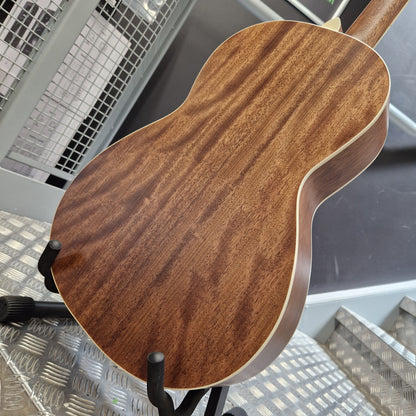 Pre-Owned PRS P20 Tonare Parlor Electro-Acoustic - Black Close-up of the back of a wooden acoustic guitar or ukulele on a black stand, showing a rich brown wood grain finish and light binding, photographed in an industrial setting.