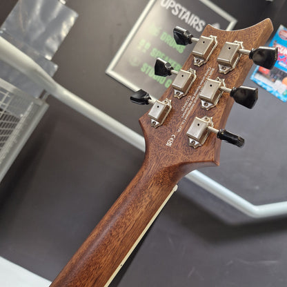 Pre-Owned PRS P20 Tonare Parlor Electro-Acoustic - Black Close-up of the headstock of an electric guitar, showing six black tuning pegs, silver tuning machines, and the back of the brown wood neck in a store setting.