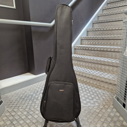 Pre-Owned Enya Nova Go SP1 Carbon Fibre Electro-Acoustic - Matte Black A black guitar or ukulele hard case standing on a metal staircase landing, with gray steps and a dark wall in the background.