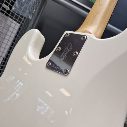 Pre-Owned Music Man Sterling Sub Series Ray 4 Bass - White Close-up of the lower bout body of a white Gibson electric guitar, showing the chrome 'Gibson' brand plate and part of the natural wood neck.