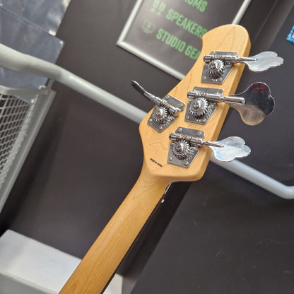 Pre-Owned Music Man Sterling Sub Series Ray 4 Bass - White Close-up of the headstock of a bass guitar with a natural wood finish and four silver heart-shaped tuning keys, photographed in a store setting.