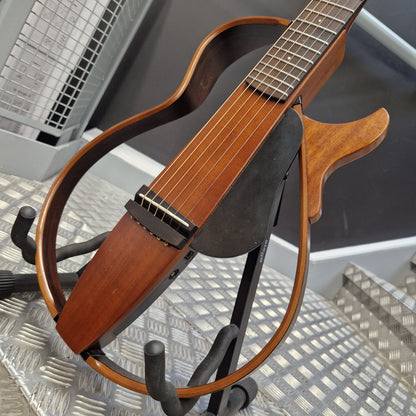 Pre-Owned Yamaha SLG200S Silent Guitar Electro-Acoustic - Natural A wooden six-string acoustic guitar with a distinctive curved body and black headstock, displayed on a black stand on a diamond plate floor.