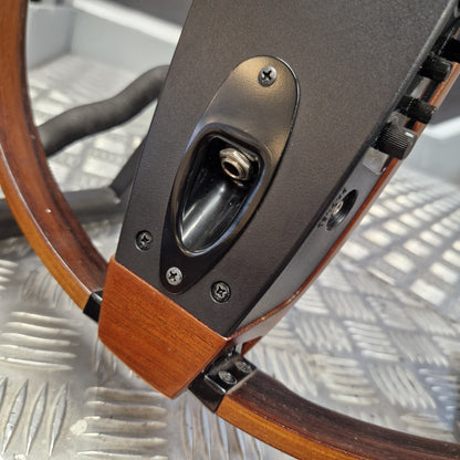 Pre-Owned Yamaha SLG200S Silent Guitar Electro-Acoustic - Natural Close-up of a steering wheel assembly with a dark gray central console, wood-grain trim, and a metallic diamond-plate floor in the background.