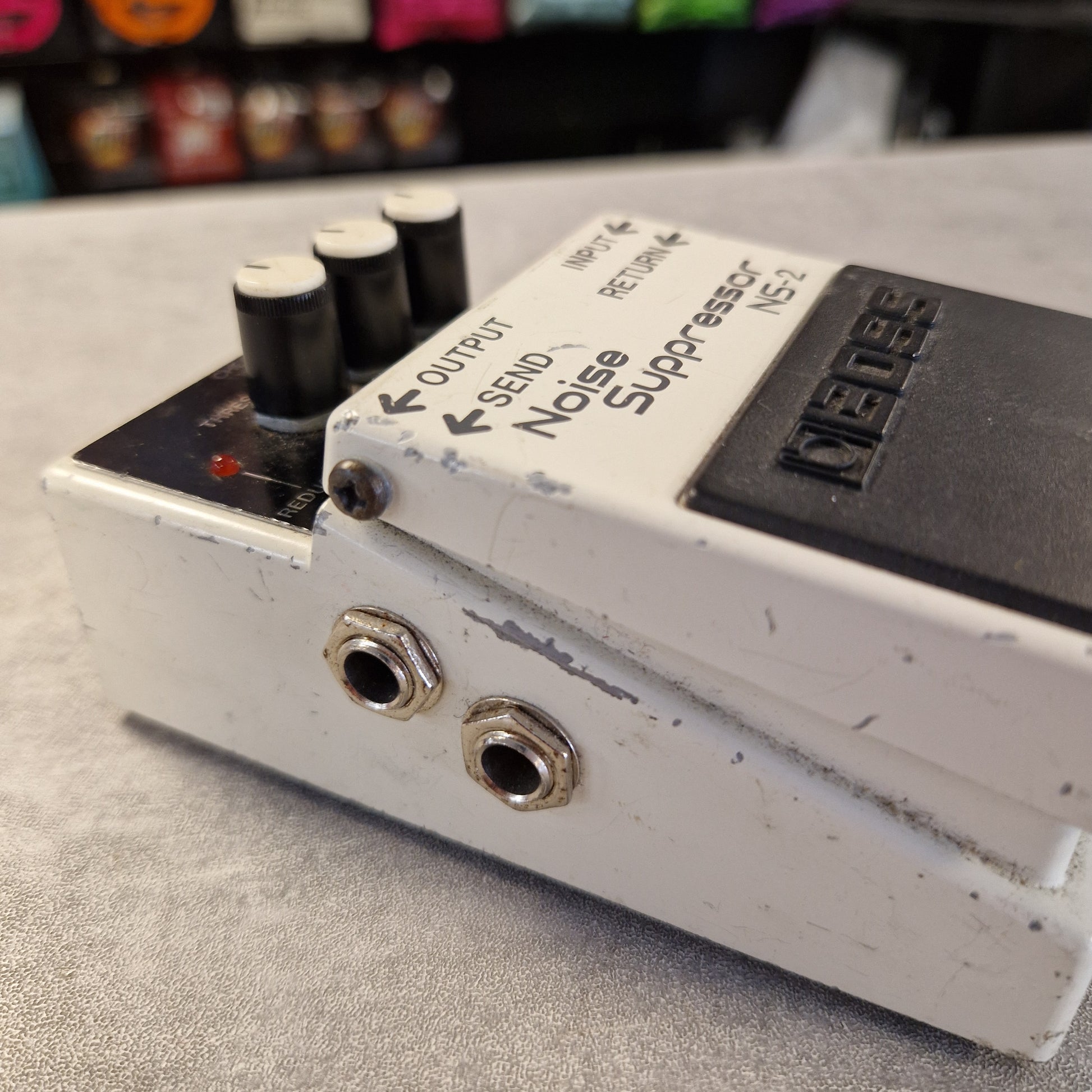 Pre-Owned Boss NS-2 Noise Suppressor Pedal A used Fuzz Face 2 noise suppressor guitar pedal with a white metal casing, black knobs, and a black footplate, resting on a gray surface.