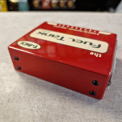 Pre-Owned T. Rex Fuel Tank Junior Power Supply A red T.Rex Fuel Tank electronic device with a glossy finish, resting on a gray textured surface.