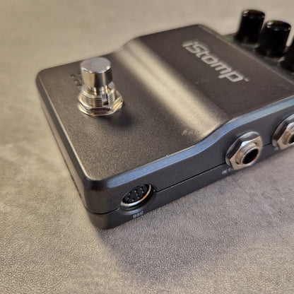 Pre-Owned DigiTech iStomp Switchable Multi Guitar Effects Pedal A close-up shot of a black iStomp guitar effects pedal on a textured gray surface, showing the footswitch, input jack, output jacks, and the iStomp logo.