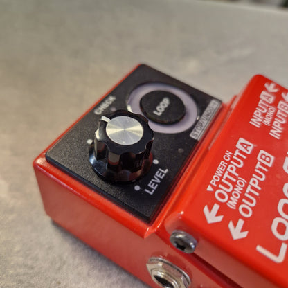 Pre-Owned Boss RC-1 Loop Station Pedal A close-up of a red and black Loopsound Logic Delay pedal with a silver checkered knob and white printed controls on a gray surface.