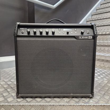 Pre-Owned Line 6 Spider V 120 Mk II Guitar Combo Amplifier A black Line 6 Synergy 700 guitar amplifier with a front speaker grille, set on a diamond plate metal surface with stairs in the background.