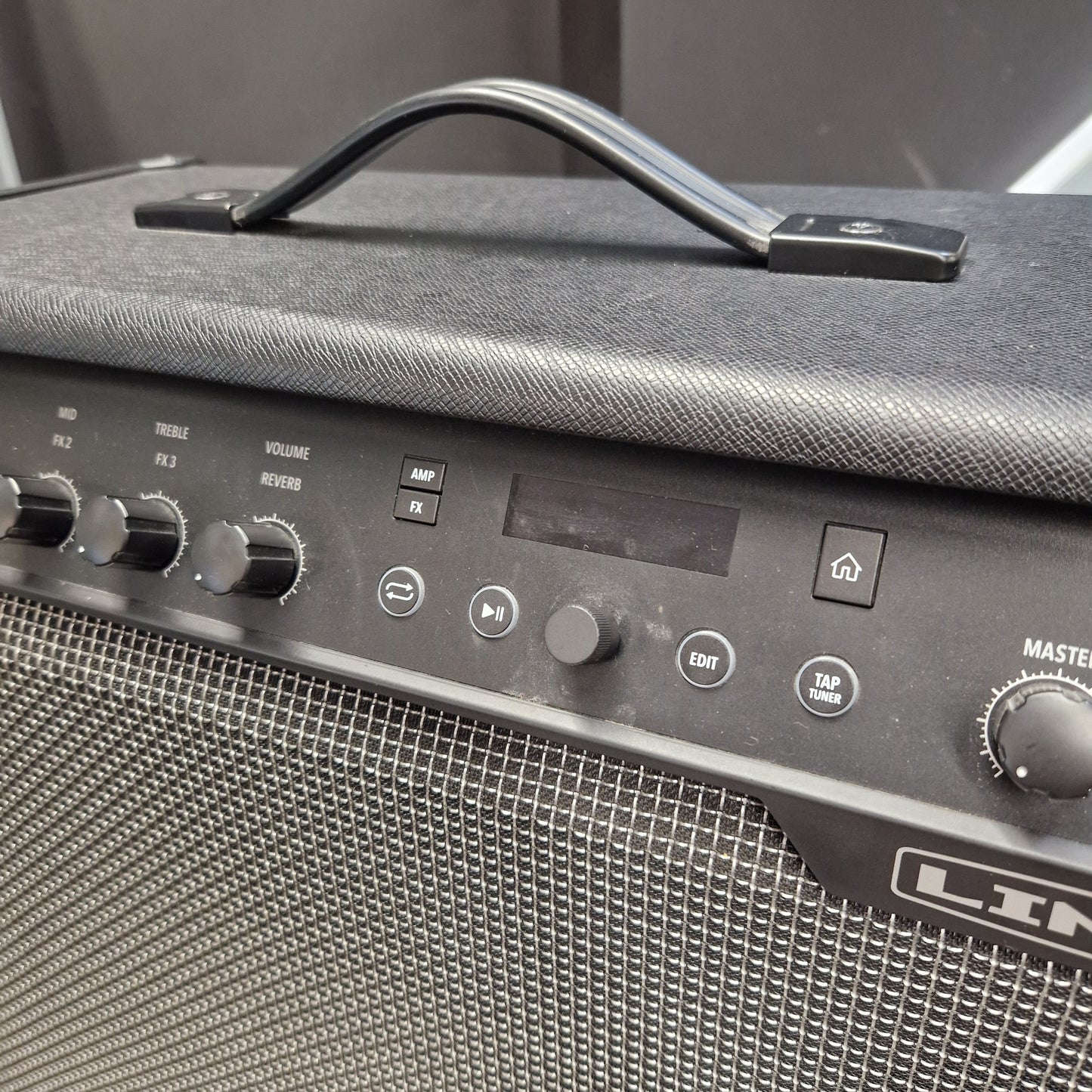 Pre-Owned Line 6 Spider V 120 Mk II Guitar Combo Amplifier Close-up of a black Line 6 portable guitar amplifier, showing the top handle, textured fabric cover, control knobs, speaker grille, and part of the master volume dial.