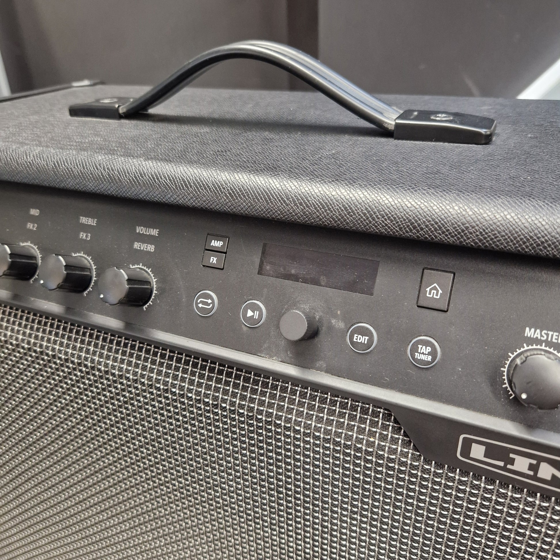 Pre-Owned Line 6 Spider V 120 Mk II Guitar Combo Amplifier Close-up of a black Line 6 portable guitar amplifier, showing the top handle, textured fabric cover, control knobs, speaker grille, and part of the master volume dial.
