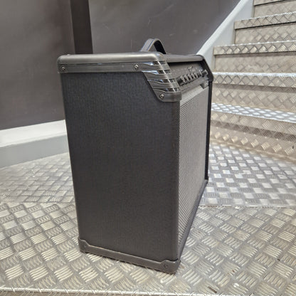Pre-Owned Line 6 Spider V 120 Mk II Guitar Combo Amplifier A black guitar amplifier with a textured fabric cover and a top handle, positioned on a diamond plate metal staircase.