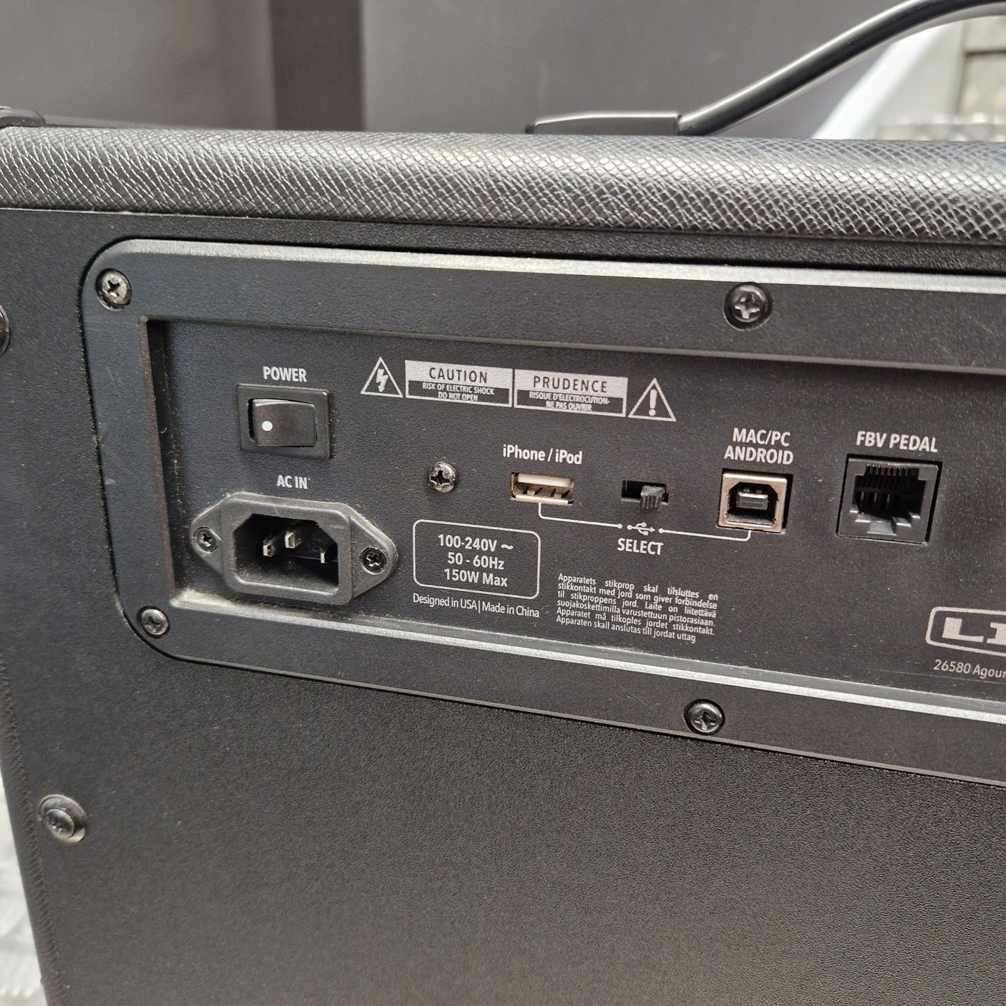 Pre-Owned Line 6 Spider V 120 Mk II Guitar Combo Amplifier Close-up of the rear panel of a black guitar amplifier, showing input jacks, power switch, USB and audio outputs, and warning labels.