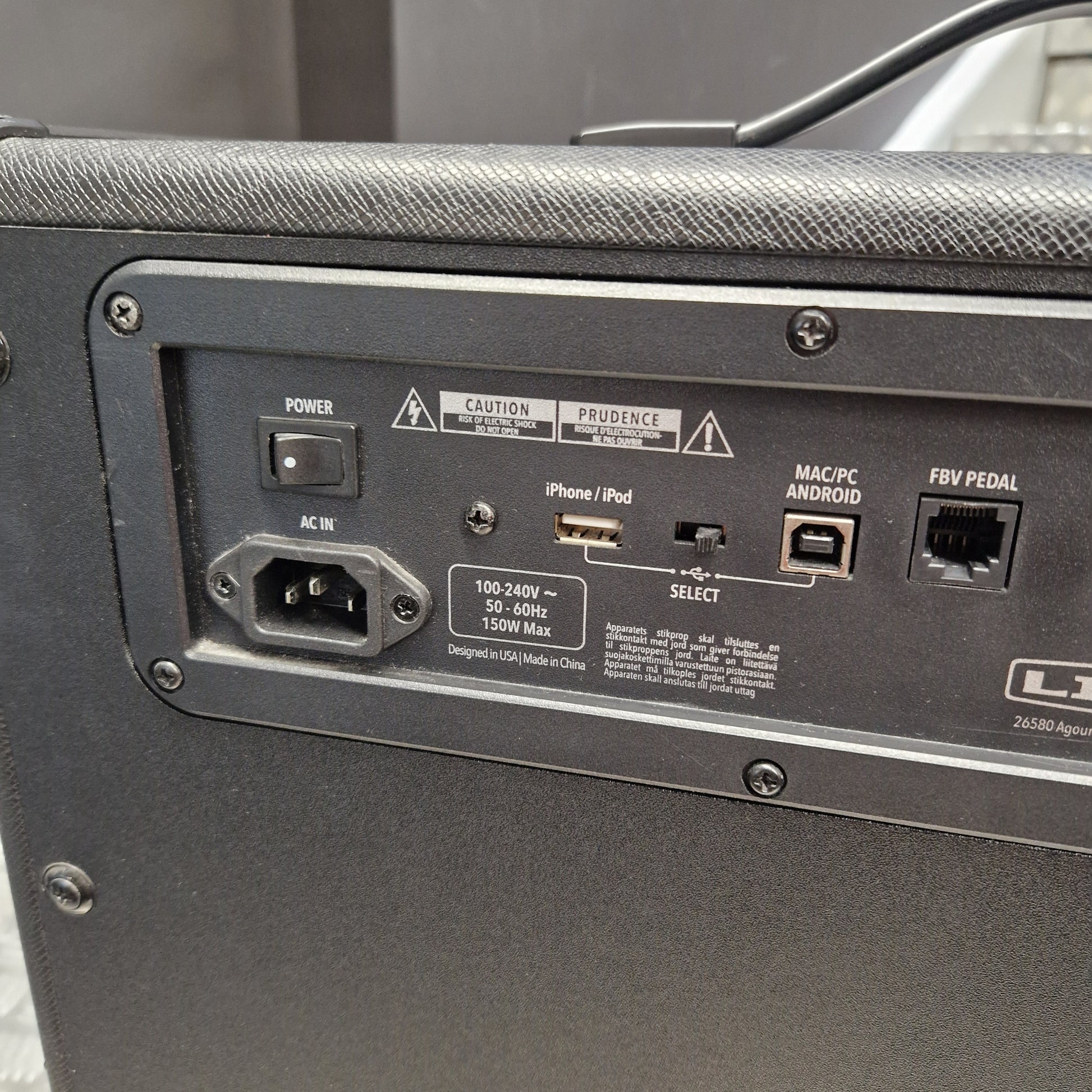 Pre-Owned Line 6 Spider V 120 Mk II Guitar Combo Amplifier Close-up of the rear panel of a black guitar amplifier, showing input jacks, power switch, USB and audio outputs, and warning labels.