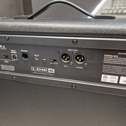 Pre-Owned Line 6 Spider V 120 Mk II Guitar Combo Amplifier Close-up of the rear panel of a black Line 6 mobile amplifier, showing input and output jacks, labels, and a handle on top.