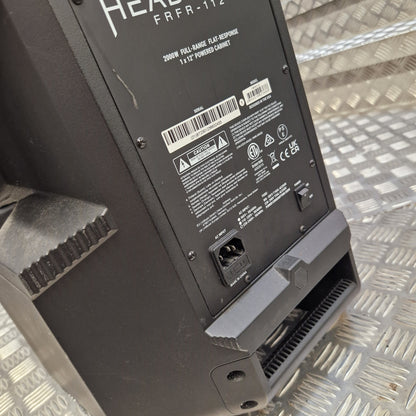 Pre-Owned Headrush FRFR-112 Full Range Powered 1x12 Speaker Close-up of the rear panel of a black HEBEY FRFR-112 powered speaker, showing the power input, barcode, and regulatory labels, resting on a diamond plate metal surface.