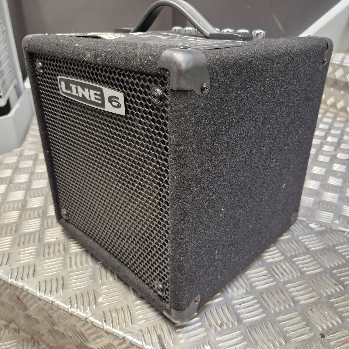 Pre-Owned Line 6 LowDown Studio 110 75w Digital Bass Combo A used Line 6 mini guitar amplifier with a black textured cloth cover and metal grille, resting on a diamond plate metal surface.