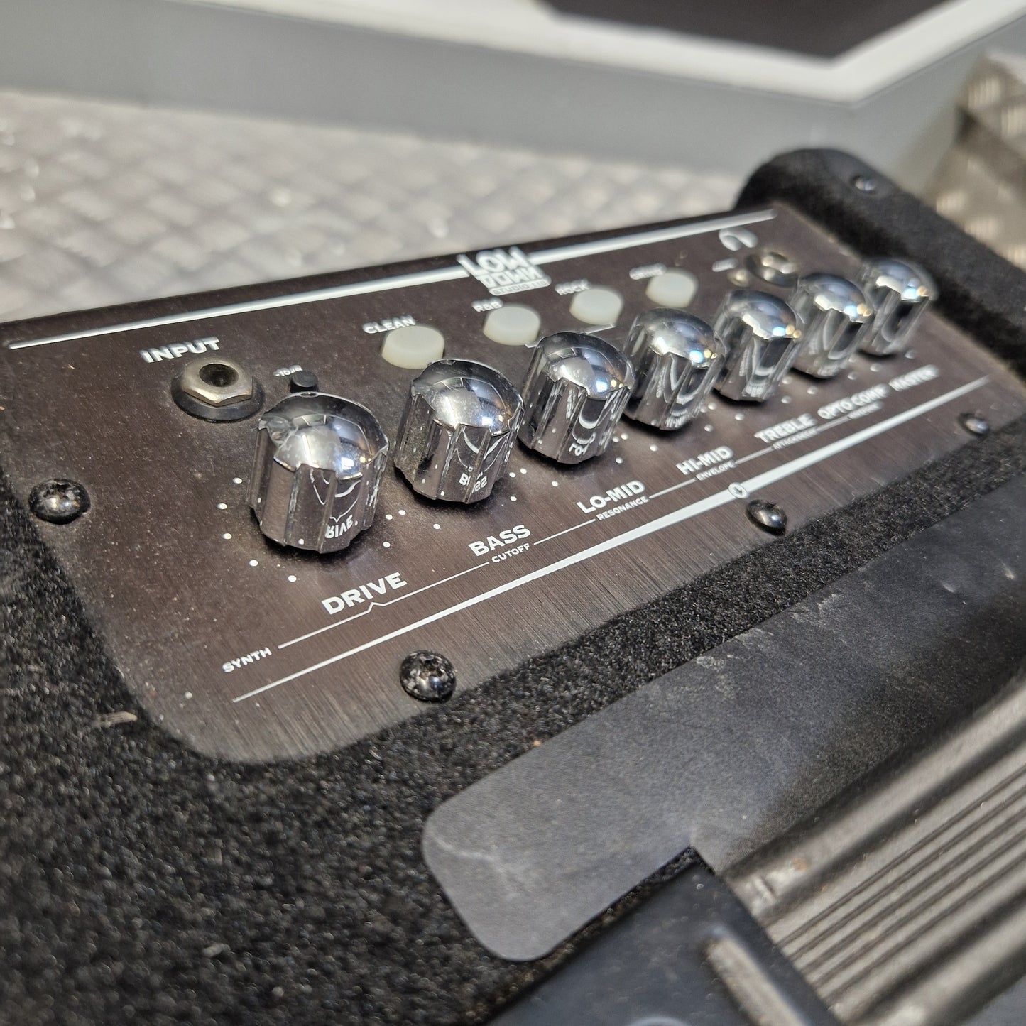Pre-Owned Line 6 LowDown Studio 110 75w Digital Bass Combo Close-up of the control panel of a black Focal effects pedal, showing silver knobs for Drive, Bass, and Low-Mid, with a textured black carpeted surface.