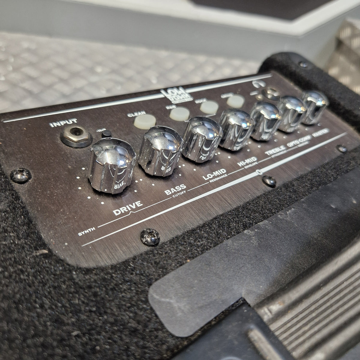 Pre-Owned Line 6 LowDown Studio 110 75w Digital Bass Combo Close-up of the control panel of a black Focal effects pedal, showing silver knobs for Drive, Bass, and Low-Mid, with a textured black carpeted surface.