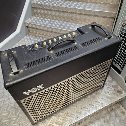 Pre-Owned Vox VT100 Valvetronix 100w Electric Combo A Vox guitar amplifier with a black front grille and cream-colored knobs, resting on diamond plate metal steps.