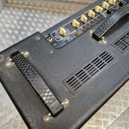 Pre-Owned Vox VT100 Valvetronix 100w Electric Combo Close-up of a black textured guitar amplifier head with cream-colored control knobs, a footswitch, and vent grilles on a diamond-plate metal floor.